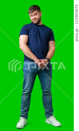 Man standing with a thoughtful expression in a casual outfit against a green background Man standing with a thoughtful expression in a casual outfit against a green background 122903673