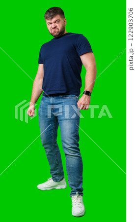 Man expressing confusion with crossed arms in front of a bright green background 122903706