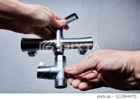 Hands holding bathtub faucet combo with control handles, preparing for mounting in shower room. Hands holding bathtub faucet combo with control handles, preparing for mounting in shower room. 122904470