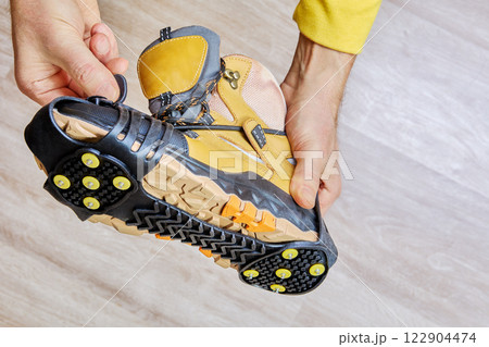 Attaching ice cleats to a hiking boot for better traction on slippery surfaces. Attaching ice cleats to a hiking boot for better traction on slippery surfaces. 122904474