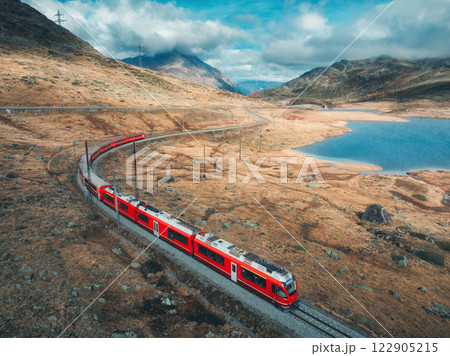 Aerial view of red train near alpine mountain lake and cloudy sky 122905215