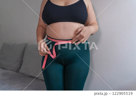 Fat women has overweight and she measuring abdomen girth with measure tape 122905519