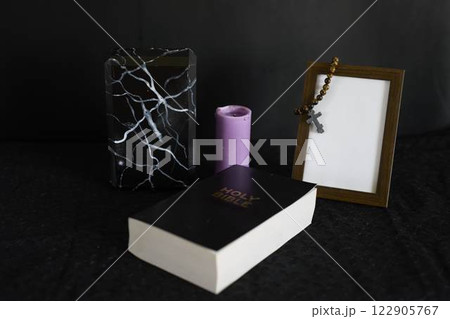 funeral, photo frame, candles, a marble urn for ashes, holy bible and spiritual bracelet with black cross 122905767