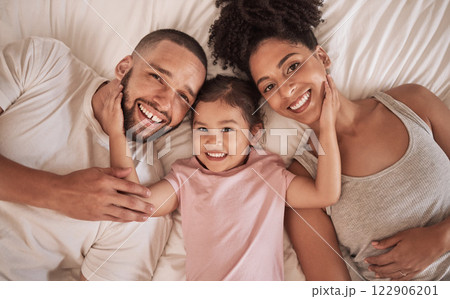 Family happy, child and above bed with parents in the morning, funny face in house and relax after sleeping together in home. Portrait of happy mother and dad smile with girl kids in home bedroom 122906201