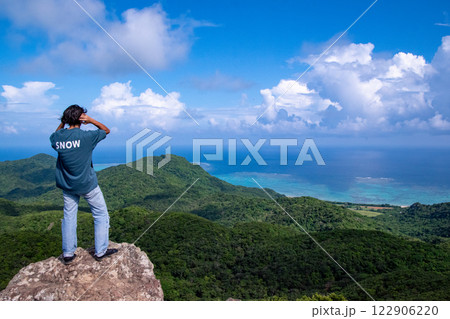 山の頂上から南の島の海を眺める男性 122906220