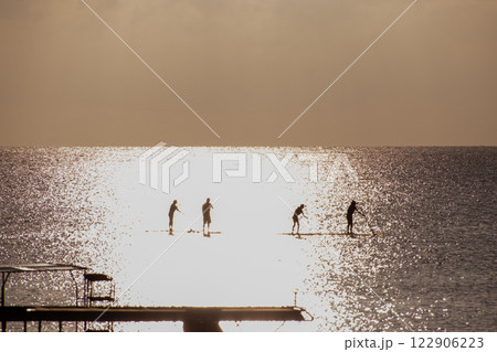 サンセットの海でサップを楽しむグループ サンセットの海でサップを楽しむグループ 122906223