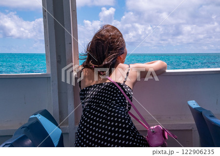 フェリーから沖縄の美しい海を眺める女性の後ろ姿 122906235