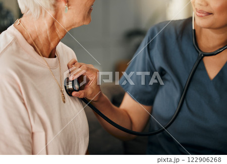 Cardiology consultation, doctor and senior woman consulting about healthcare on living room sofa in retirement home. Hand of nurse with stethoscope while helping elderly patient with medical service 122906268