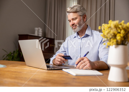 Mature caucasian man working at the laptop and looking confident Mature caucasian man working at the laptop and looking confident 122906352