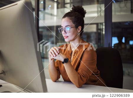 Night, research and report with a business woman working on a computer in her startup office at night. Thinking, idea and technology with a young female entrepreneur at work on a desktop in a company 122906389