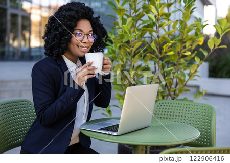 Business woman working on laptop and drinking coffee in a street cafe 122906416
