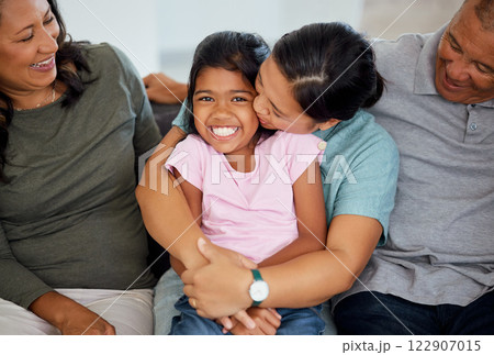 Portrait, girl with grandparents in living room as mother kiss and hug child on the sofa or couch. Latino family and young kid happy to enjoy bonding with old grandmother and man at home with love 122907015