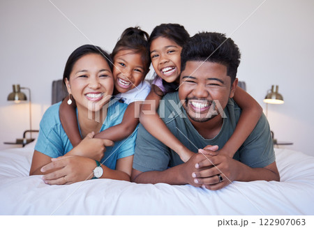 Portrait of a happy Asian family on the bed with a smile on their face. Multicultural Indian family in their bedroom smiling, laughing and having fun. Loving mom, dad and kids bond together at home 122907063