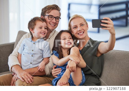 Family, happy and phone selfie on the sofa and smile for a social media post. Mother, father and kids together, bonding and carefree weekend in the living room and taking a picture with smartphone Family, happy and phone selfie on the sofa and smile for a social media post. Mother, father and kids together, bonding and carefree weekend in the living room and taking a picture with smartphone 122907188