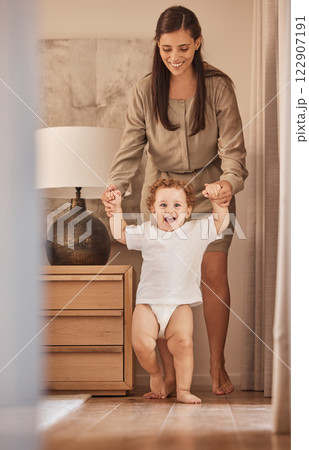 Love, mother and baby learning to walk while holding hands for support and child development. Happy, excited, and cheerful toddler walking together with help of mom in family home. 122907191