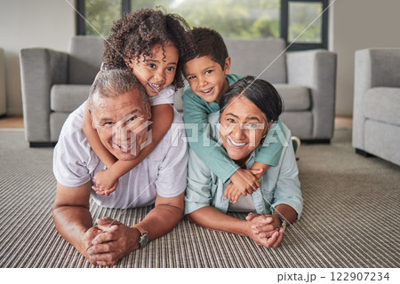 Grandparents, children or bonding in fun play game on house or family home living room floor. Portrait, smile or happy senior man and mature woman babysitting grandchildren or kids together in lounge 122907234