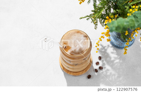Cold coffee latte or mocha in a glass with milk and ice on a light background  122907576