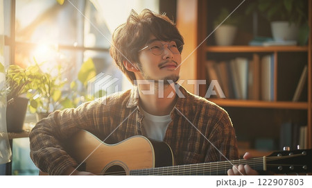 リラックスして部屋でギターを弾く男性 122907803