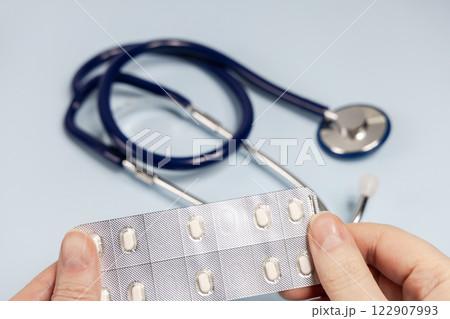 Female hands holding pills in blister. Prescription medication 122907993