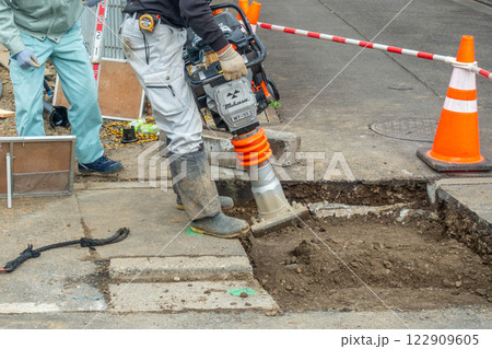 道路転圧　タンピングランマーで地面を突き固める　現場作業員 122909605