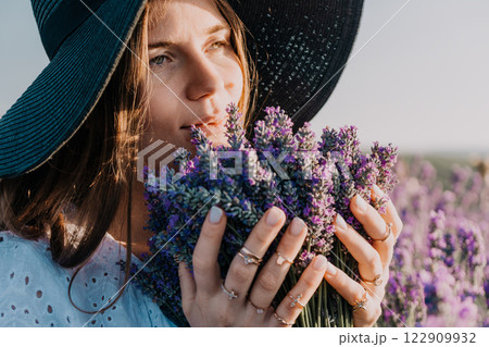 Woman in Hat Smelling Lavender Flowers in a Field 122909932