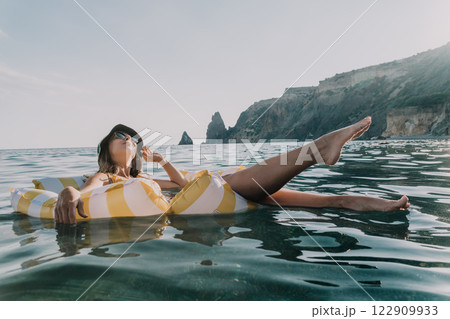 Woman, Inflatable, Beach: Relaxing on a yellow striped inflatable raft in the sea. 122909933