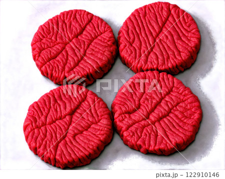 A close-up of raw ground beef patties being seasoned with salt and pepper. The beef is finely textured, slightly moist, A close-up of raw ground beef patties being seasoned with salt and pepper. The beef is finely textured, slightly moist, 122910146