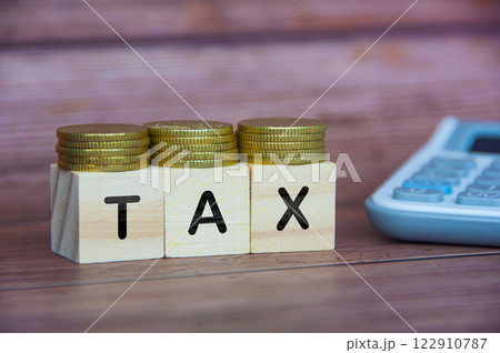 TAX word on wooden cube with golden coins and calculator background. Taxation concept. 122910787