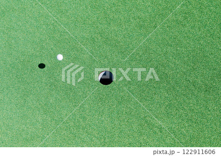 ゴルフボールがカップへ向かってグリーン上を転がってゆくイメージ 122911606