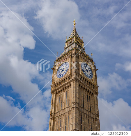 A close up shot of the iconic Big Ben clock tower in London, showing intricate architectural details against a bright blue sky. 122912590