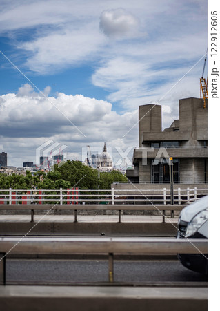 A distant perspective reveals the dome of St. Paul Cathedral, framed by modern buildings and trees from a bridge spanning the Thames. A distant perspective reveals the dome of St. Paul Cathedral, framed by modern buildings and trees from a bridge spanning the Thames. 122912606