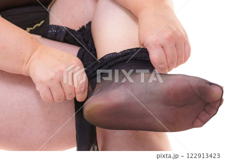 Woman plus size puts on black nylon stockings Woman plus size puts on black nylon stockings 122913423