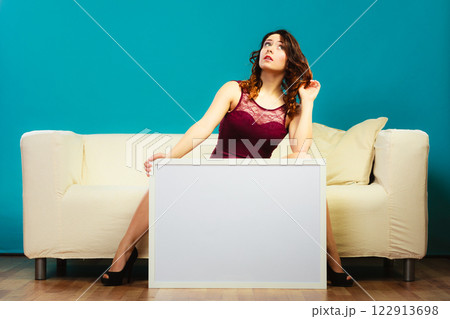woman on sofa holding blank presentation board. 122913698