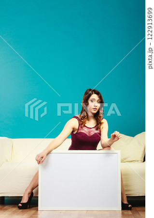 woman on sofa holding blank presentation board. 122913699