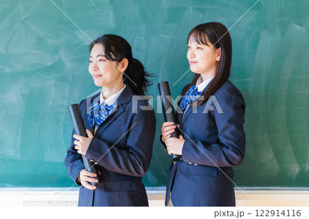 黒板の前で卒業証書を持つ女子生徒 122914116
