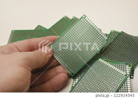 A green breadboard for electronics. The printed circuit board is in your hand. A green breadboard for electronics. The printed circuit board is in your hand. 122914343