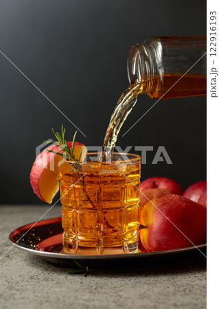 Apple juice is poured from a bottle into a glass. Apple juice is poured from a bottle into a glass. 122916193