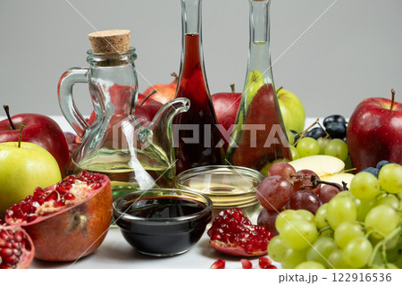 Different types of vinegar apple, wine and pomegranate in vinegar bowls among fruits. 122916536