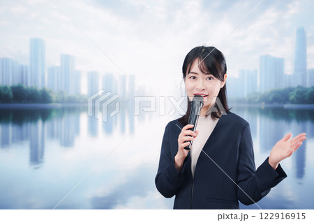 街角でマイクを使って演説をする若い女性 122916915