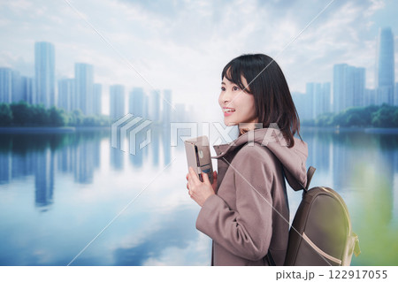 コートを着てスマホを使いながら外を歩く若い女性 コートを着てスマホを使いながら外を歩く若い女性 122917055