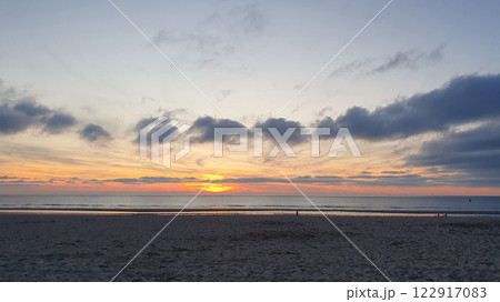 Beautiful evening sunset by the beach. Sunrise at sea with much clouds, sand and water. 122917083