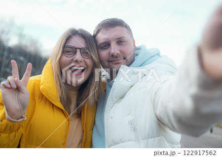 Photo of young Caucasian couple happy positive smile make selfie wave hand hello hi near a lake at winter Photo of young Caucasian couple happy positive smile make selfie wave hand hello hi near a lake at winter 122917562