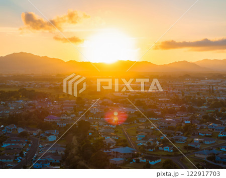 Aerial view of a residential area on Kauai island during sunset, with mountains in the background, lush greenery, and scattered clouds in the sky. Aerial view of a residential area on Kauai island during sunset, with mountains in the background, lush greenery, and scattered clouds in the sky. 122917703