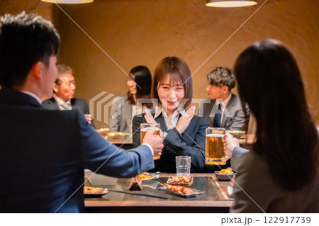 居酒屋で先輩社員にアルコールを勧められて断る女性社員 122917739