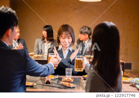 居酒屋で先輩社員にアルコールを勧められて断る女性社員 122917746