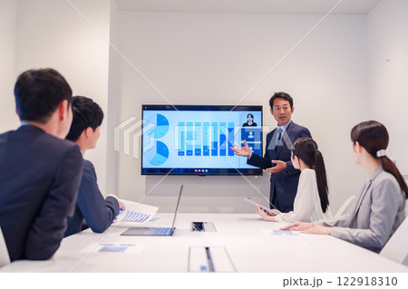 会議で資料を見ながらプレゼンをする中年のオフィスワーカー 122918310