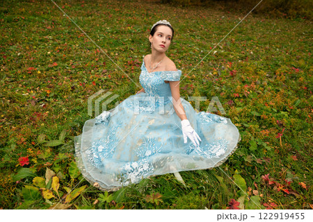 Beautiful brunette girl in a blue ball gown in a colorful forest Beautiful brunette girl in a blue ball gown in a colorful forest 122919455