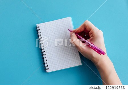Female hands with perfect manicure holding pen and spiral notebook as a mockup for your design. Blue background, flat style Female hands with perfect manicure holding pen and spiral notebook as a mockup for your design. Blue background, flat style 122919888