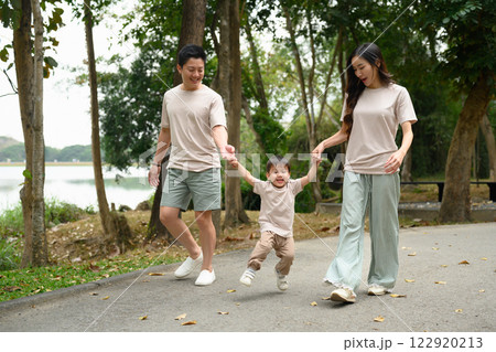 Happy family walking together along a scenic park pathway Happy family walking together along a scenic park pathway 122920213