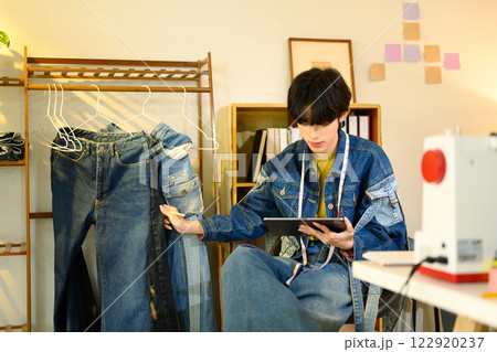 Young small business entrepreneur checking order on digital tablet tablet in a creative workspace 122920237